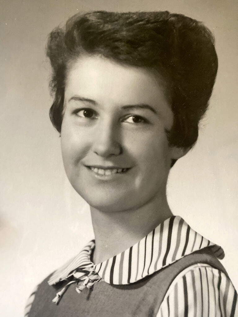 A past photo of Marjorie smiling, she has a short haircut and a blouse with striped details.