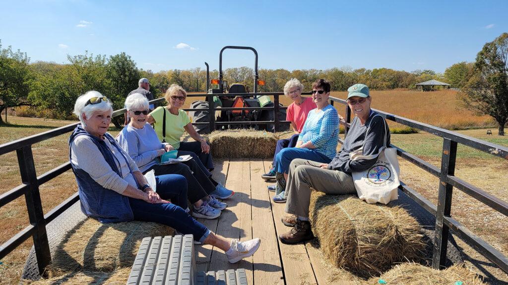Group of women on farm hay bales, having fun on a tractor-pulled hay bale ride.