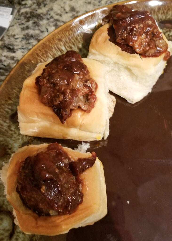 A tantalizing trio of meatball sliders, perfectly placed on a plate with fluffy buns, beckoning you to take a bite.