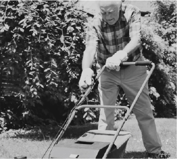 Greyscale photo of senior man struggling with lawnmower