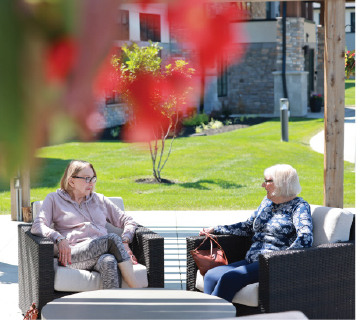Two Senior residents seated outdoors on a sunny day chatting