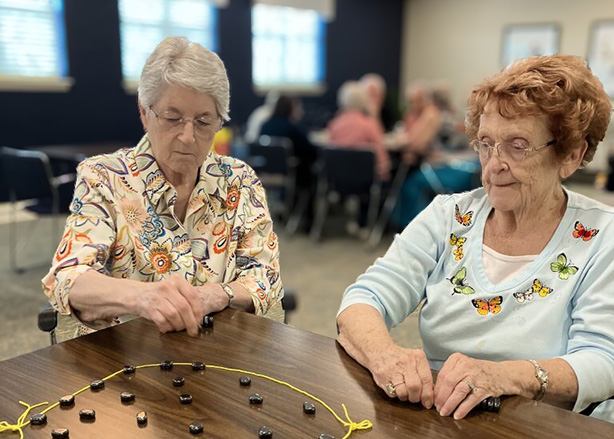 Two senior women work on a project together at The Madison Senior Living.