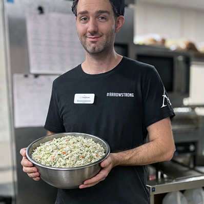 Culinary team member at The Madison Senior Living smiles while holding a large bowl of chef-prepared coleslaw.
