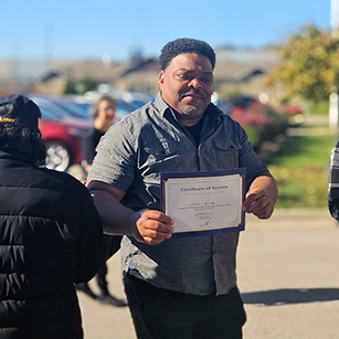 A man on the Madison team receives a certificate honoring his service during a Veterans celebration.