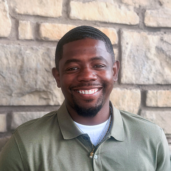 Mickale Odems, Plant Operations Director at The Madison Senior Living, smiling in a professional headshot with short dark hair, a trimmed goatee, a green polo shirt, and a light stone wall background.
